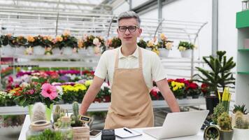 A Caucasian man in a florist shop, standing behind the table with various plants, smiling at the camera. video