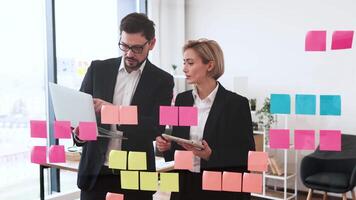 Team of male and female professionals collaborating on brainstorm with sticky notes, modern workspace video