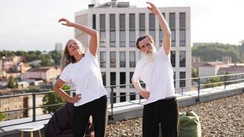 Senior man and woman practicing physical fitness outdoors, improving flexibility and health, sunny day. video