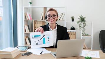 Potrtait of businesswoman in thirties presenting financial graphs during online meeting using laptop, showcasing growth data. video