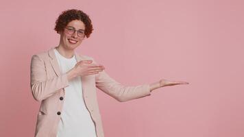 Caucasian attractive man showing thumbs up and pointing right empty place advertising area for commercial text copy space for goods promotion advertisement. Guy isolated on pink background. Lifestyle video