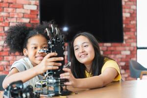 Diverse Kids Building a Robot Arm in a Science Workshop, Young Girls Engaged in Robotics and STEM Learning, Two Girls Exploring Technology and Innovation, Future Engineers photo