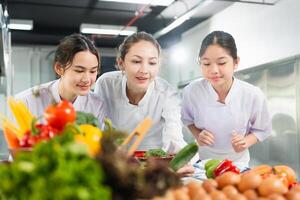 Chef and Students Learning Culinary Skills in Kitchen, Women Preparing Fresh Ingredients for Cooking Class, Professional Chef Mentoring Young Cooks in a Bright Kitchen photo