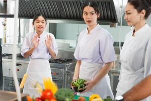Culinary Students Engaged in Learning with Instructor in Kitchen, Young Chefs Practicing Cooking Techniques with Fresh Ingredients, Women in Chef Uniforms Discussing Food Preparation in Kitchen photo