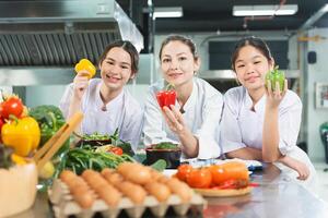 Young Chefs and Mentor with Fresh Vegetables in Culinary Class, Smiling Women in Chef Uniforms Holding Bell Peppers in a Kitchen, Female Students and Instructor with Produce, Healthy Cooking Education photo