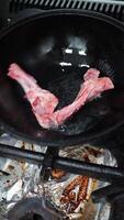 Professional chef wearing protective gloves carefully lowering raw lamb bones into sizzling hot oil within large wok on gas stove, executing traditional culinary technique with precise skill video