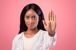 Thank you but no concept. Serious black woman making stop gesture on pink studio background. Assertive African American woman showing denial sign, expressing her rejection, refusing something photo