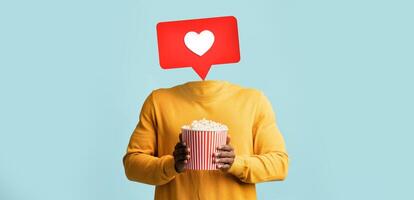 A person holds a bucket of popcorn while a heart icon appears above where their head should be. This visual represents social media interaction and engagement in a playful way. photo