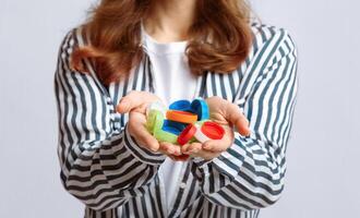 Lots Of Colorful Plastic Lids Bottle Caps In Hands Of Unrecognizable Lady. Eco-Friendly Woman Agitating For Zero Waste Living And Garbage Sorting, Standing On Grey Studio Background, Closeup Shot photo