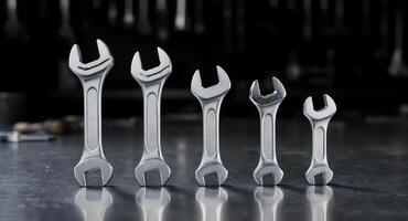Five precision engineered chrome wrenches of varying sizes standing upright in a studio photo