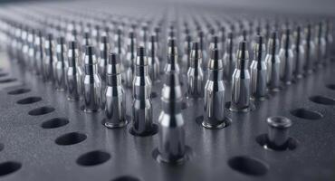 Rows of shiny metallic ammunition cartridges arranged in a precise grid pattern photo
