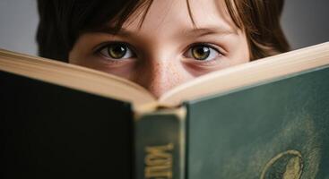 Child curious eyes peeking over an open book, immersed in reading and learning photo