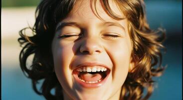 Joyful child with curly hair laughing heartily with eyes closed in warm sunlight photo