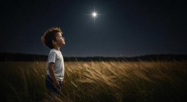 Young boy looking up at a bright shining star in the night sky over a field photo