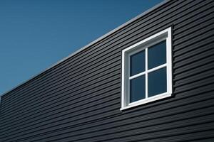 Modern building facade with dark grey corrugated metal siding and white window photo
