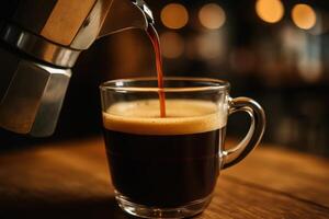 Fresh espresso coffee poured from moka pot into glass cup on wooden table photo