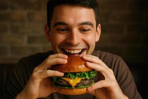 Happy young man with a wide smile about to bite into a delicious cheeseburger photo