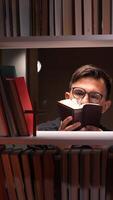 A man in glasses reading a book in a library video