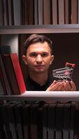 A man holding a shopping cart in front of a shelf full of books video