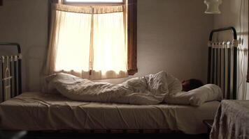 A man is sleeping in a bed next to a window video