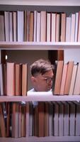 vertical bibliotecário olhando para livro em biblioteca estante às noite video