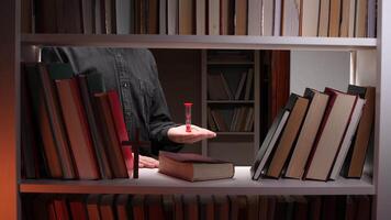 A person holding a red object in front of a book shelf video