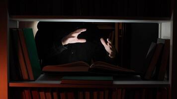 A person is holding a book in front of a book shelf video