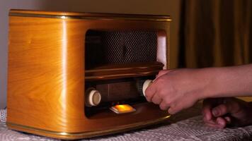 A person is turning on a radio in front of a wooden radio video