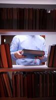vertical Librarian holding book between bookshelves in library video