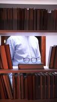 vertical Librarian holding eyeglasses in library at night, surrounded by books video