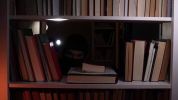 A person in a hoodie is looking at a book on a shelf video