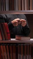 A person holding a rosary in front of a book shelf video