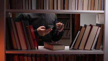 A man is looking at a phone in a bookcase video