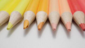Close-Up of Vibrant Warm-Toned Colored Pencils Lined Up on a White Surface in Soft Light video