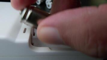 Close-up of Hand Placing Batteries Into a White Charger Device on a Clean Surface in a Modern Setting video