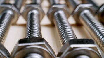 Close-up View of Shiny Metal Bolts and Nuts Arranged on a Wooden Surface in Workshop video