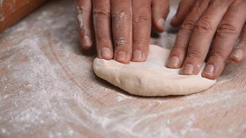 Hands rolling fresh dough with a wooden rolling pin on a floured surface in a cozy kitchen environment video