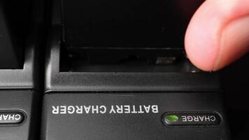 Close-up of hand activating a black portable battery charger with green indicator light in dark environment video