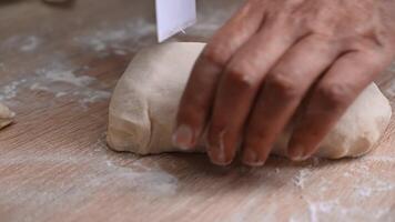 Close-up of artisan hands skillfully dividing fresh dough on a rustic wooden countertop in a warm kitchen environment video