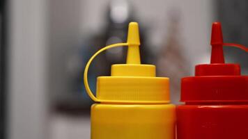 Close-up of vibrant yellow and red squeeze condiment bottles in a casual kitchen setting video