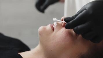 Esthetician applying numbing cream on patient's lips before injects filler. video