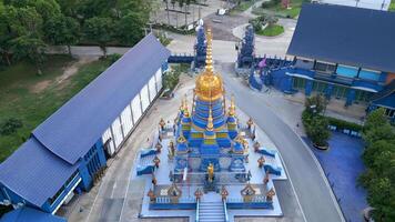 Aerial view of Wat Paknam Blue Temple in Chiang Rai, Thailand, showcasing its striking blue and gold architecture in peaceful urban setting. video