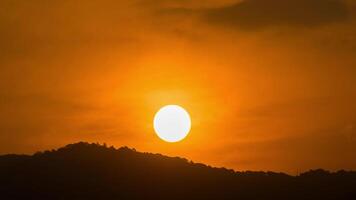 A plane flying over a mountain with the sun setting behind it video