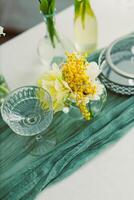 A vibrant floral arrangement in elegant glass vases on a white table with soft green fabric underneath creates a serene atmosphere that fosters relaxation and appreciation of natures beauty photo