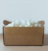 close-up of cardboard box filled with eco-friendly corn based packing peanuts Sustainable packaging for safe and conscious shipping, logistics and online shopping themes photo