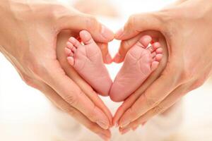 Tiny Baby Feet Held in Mother s Hands Forming a Heart Shape Symbolizing Love photo