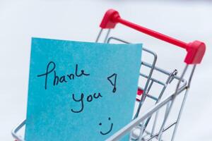 Business thank you note in shopping cart retail environment digital content close-up view gratitude concept photo