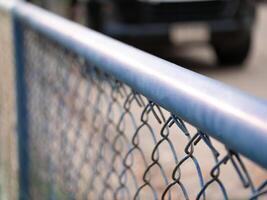 Close-up view of chain link fence with car in background urban setting photography outdoor perspective security concept photo