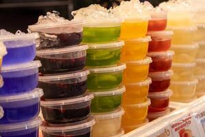 Colorful gelatin cups for sale at a local market vibrant display food stall outdoor setting eye-level view treats for all ages photo