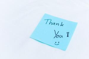 Thank you note on blue sticky pad office setting personal gesture clean environment close-up view concept of appreciation in business photo